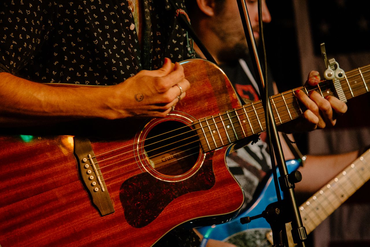 Hands playing an acoustic guitar during a live music performance in Boston.